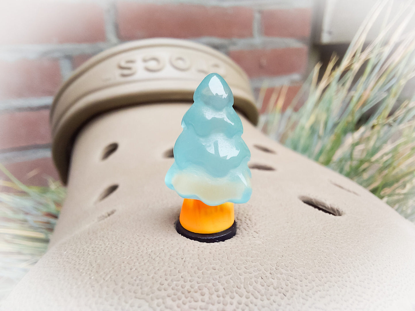 A beige shoes shoe adorned with small, glowing Christmas tree charms in a variety of soft colors, including yellow, pink, green, and blue. Each tree charm has a luminous effect, creating a festive and playful look.