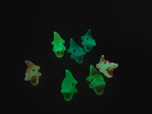 A set of glow-in-the-dark shoeodile charms adorns a shoes shoe. Each charm is shaped like a small, detailed shoeodile, appearing in a range of bright colors that glow vividly in the dark.