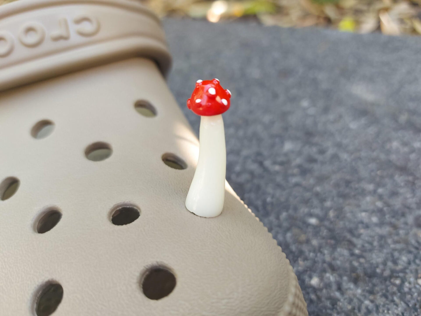 Glow in the dark forest mushroom shoe charms with white stems and red caps with white dots on a pair of shoes shoes.