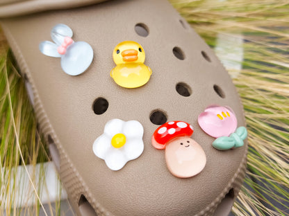 Close-up of a shoe decorated with a 5-piece jelly charm set, including two flowers, a yellow duck, a bunny with a pink bow, and a red mushroom. Each charm has a cute, soft, jelly-like appearance, adding a fun and playful vibe to the footwear.