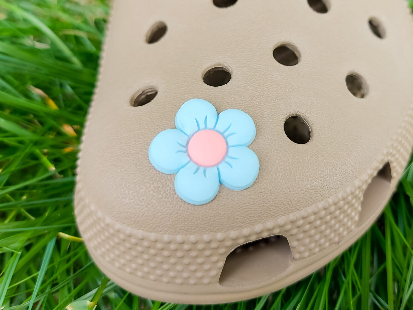 A cluster of vibrant cosmos flower charms decorates a shoes shoe, with each charm showcasing delicate petals in shades of pink, white, and purple. The intricate details of the flowers mimic real cosmos blooms, with soft gradients and textured centers