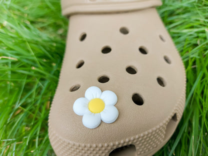 A cluster of vibrant cosmos flower charms decorates a shoes shoe, with each charm showcasing delicate petals in shades of pink, white, and purple. The intricate details of the flowers mimic real cosmos blooms, with soft gradients and textured centers