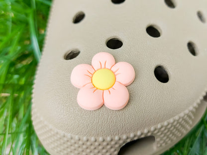 A cluster of vibrant cosmos flower charms decorates a shoes shoe, with each charm showcasing delicate petals in shades of pink, white, and purple. The intricate details of the flowers mimic real cosmos blooms, with soft gradients and textured centers