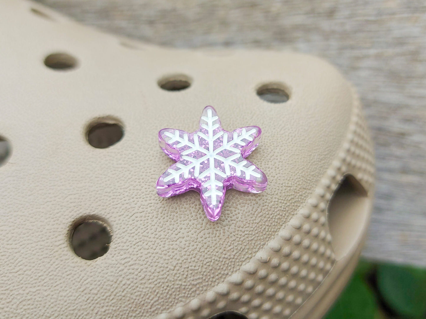 Colorful winter snowflake christmas shoe charms on a pair of shoes shoes. The snowflakes are in multiple colors and have a sparkly glitter.