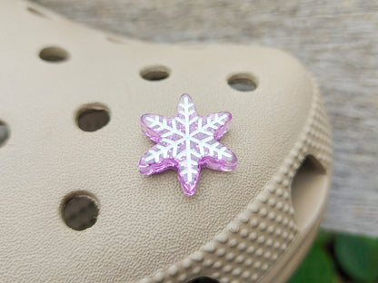 Colorful winter snowflake christmas shoe charms on a pair of shoes shoes. The snowflakes are in multiple colors and have a sparkly glitter.
