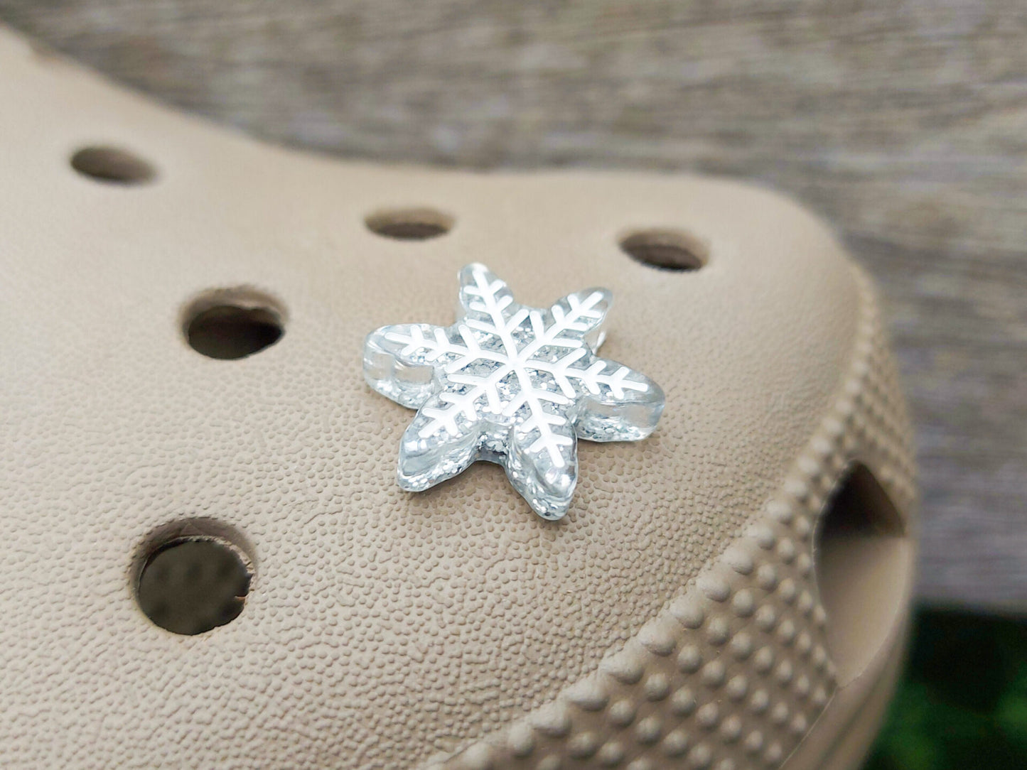 Colorful winter snowflake christmas shoe charms on a pair of shoes shoes. The snowflakes are in multiple colors and have a sparkly glitter.