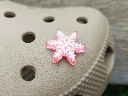 Colorful winter snowflake christmas shoe charms on a pair of shoes shoes. The snowflakes are in multiple colors and have a sparkly glitter.