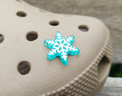 Colorful winter snowflake christmas shoe charms on a pair of shoes shoes. The snowflakes are in multiple colors and have a sparkly glitter.