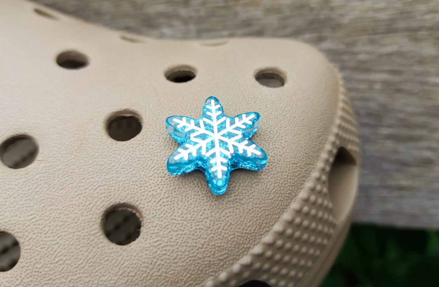 Colorful winter snowflake christmas shoe charms on a pair of shoes shoes. The snowflakes are in multiple colors and have a sparkly glitter.