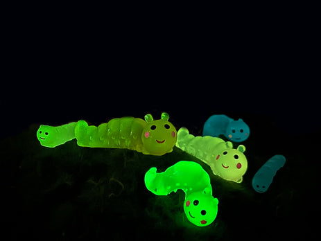 A collection of glow worm caterpillar shoe charms attached to a single shoe shoe. The charms feature caterpillar designs in various bright colors, including green, yellow, blue, pink, and orange, all designed to glow in the dark.
