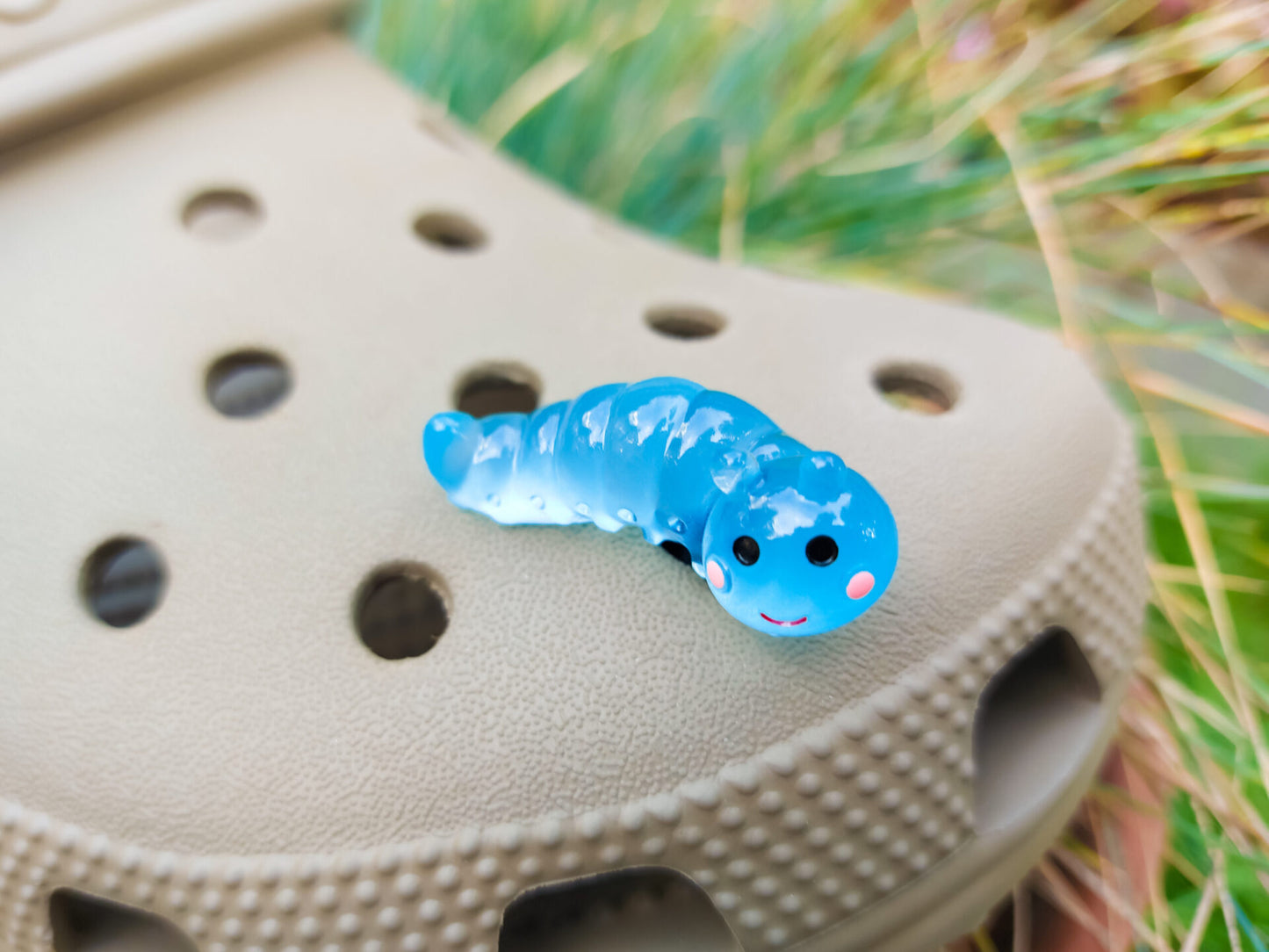 A collection of glow worm caterpillar shoe charms attached to a single shoe shoe. The charms feature caterpillar designs in various bright colors, including green, yellow, blue, pink, and orange, all designed to glow in the dark.