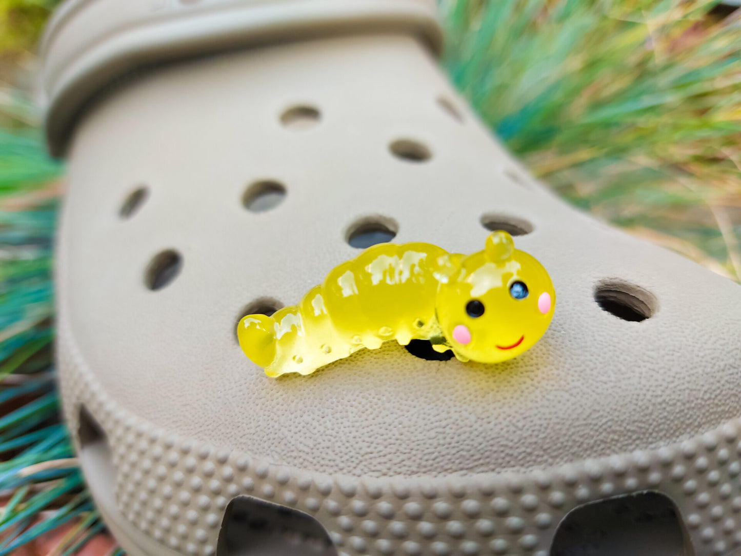 A collection of glow worm caterpillar shoe charms attached to a single shoe shoe. The charms feature caterpillar designs in various bright colors, including green, yellow, blue, pink, and orange, all designed to glow in the dark.