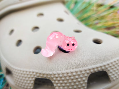 A collection of glow worm caterpillar shoe charms attached to a single shoe shoe. The charms feature caterpillar designs in various bright colors, including green, yellow, blue, pink, and orange, all designed to glow in the dark.