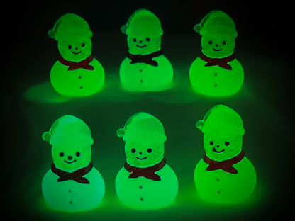 Glow-in-the-dark snowmen charms adorning a beige shoes shoe. The snowmen are in vibrant colors like green, yellow, red, purple, orange, and blue. Each snowman has a scarf, and a small hat, radiating a festive vibe perfect for the holiday season.