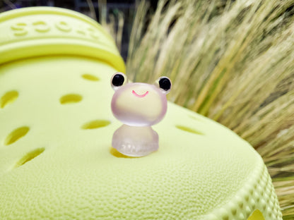 Glow-in-the-dark frog charms on a yellow shoes shoe. These playful and luminous accessories add a fun, froggy touch to your footwear, making them perfect for customizing your shoes with a whimsical and adventurous vibe.