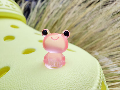 Glow-in-the-dark frog charms on a yellow shoes shoe. These playful and luminous accessories add a fun, froggy touch to your footwear, making them perfect for customizing your shoes with a whimsical and adventurous vibe.