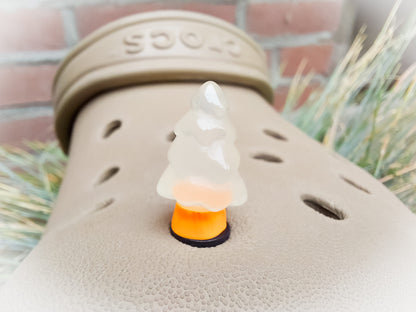 A beige shoes shoe adorned with small, glowing Christmas tree charms in a variety of soft colors, including yellow, pink, green, and blue. Each tree charm has a luminous effect, creating a festive and playful look.