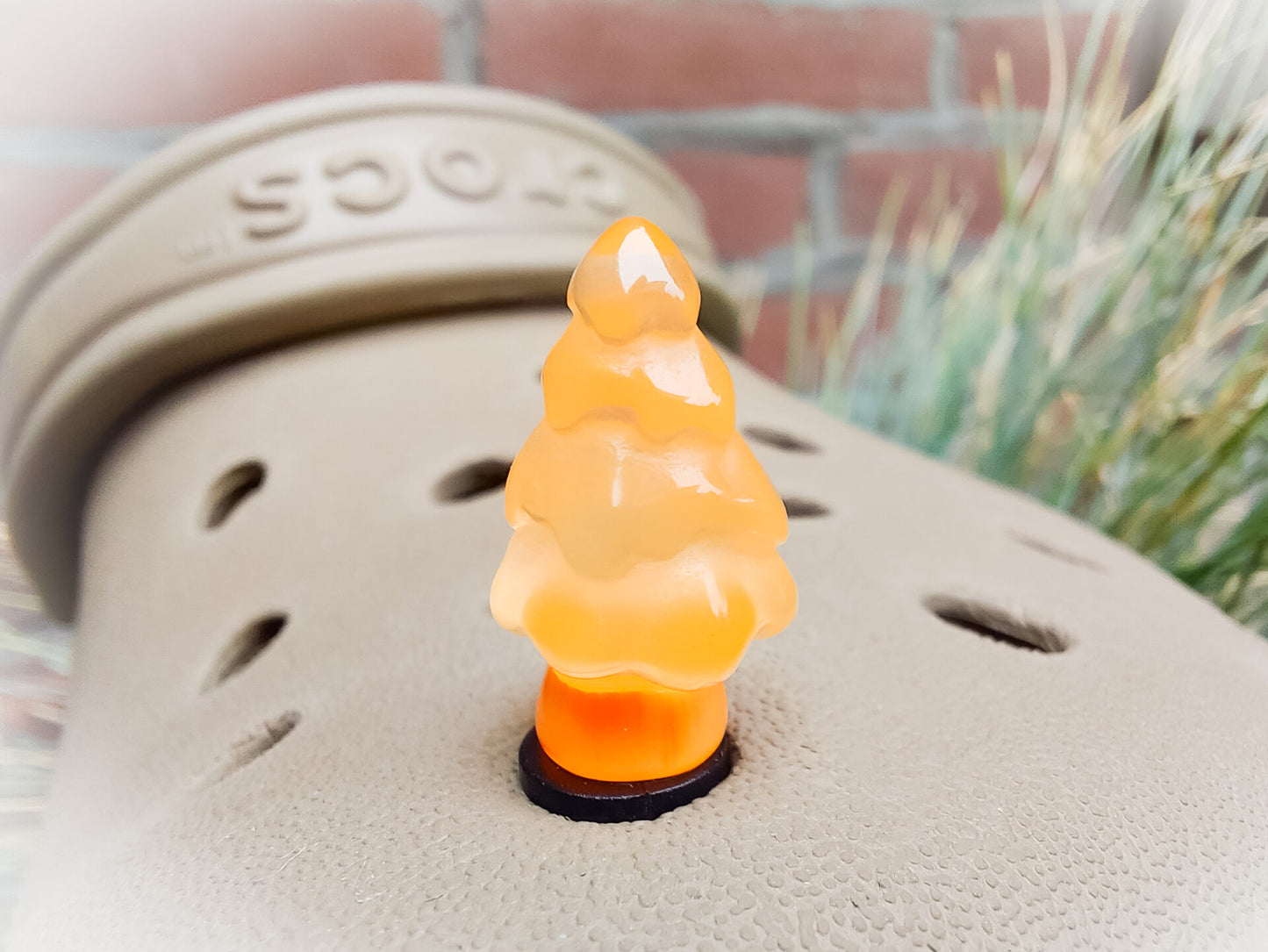 A beige shoes shoe adorned with small, glowing Christmas tree charms in a variety of soft colors, including yellow, pink, green, and blue. Each tree charm has a luminous effect, creating a festive and playful look.