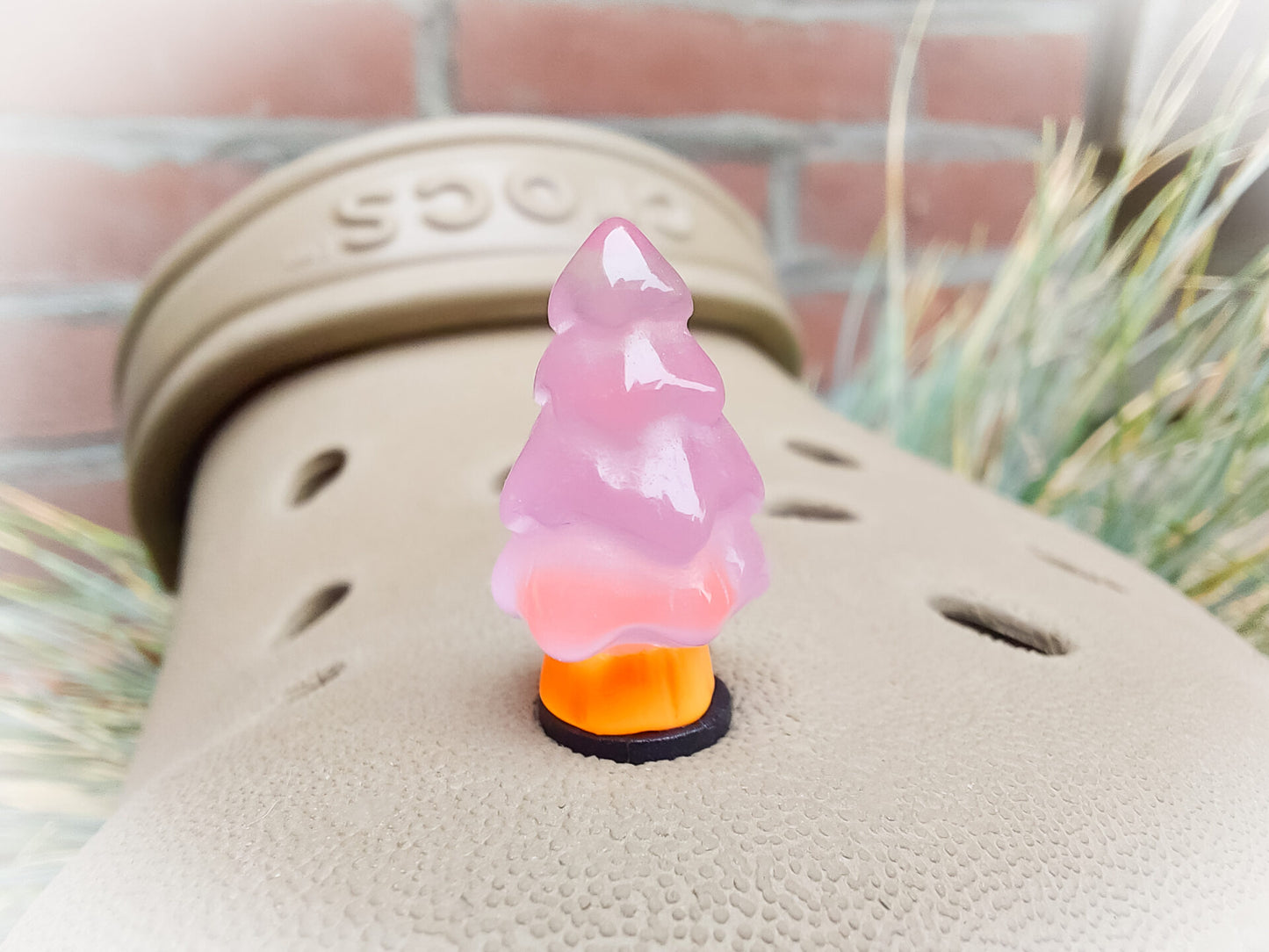 A beige shoes shoe adorned with small, glowing Christmas tree charms in a variety of soft colors, including yellow, pink, green, and blue. Each tree charm has a luminous effect, creating a festive and playful look.