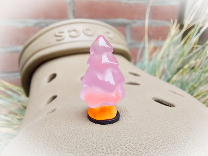A beige shoes shoe adorned with small, glowing Christmas tree charms in a variety of soft colors, including yellow, pink, green, and blue. Each tree charm has a luminous effect, creating a festive and playful look.