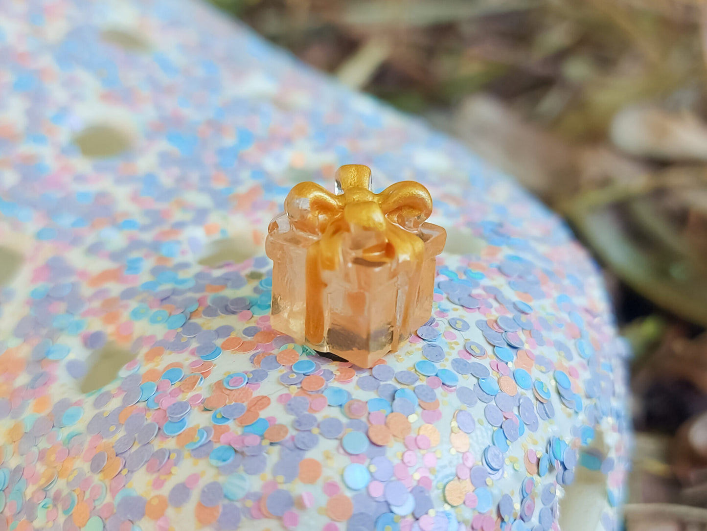 Glow in the dark christmas present charms on a colorful shoes shoe. It is a gift box with a big ribbon on top available in blue, pink, green, orange and peach. Xmas-themed perfect for the holidays.