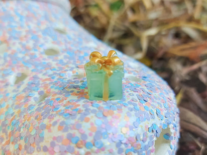 Glow in the dark christmas present charms on a colorful shoes shoe. It is a gift box with a big ribbon on top available in blue, pink, green, orange and peach. Xmas-themed perfect for the holidays.