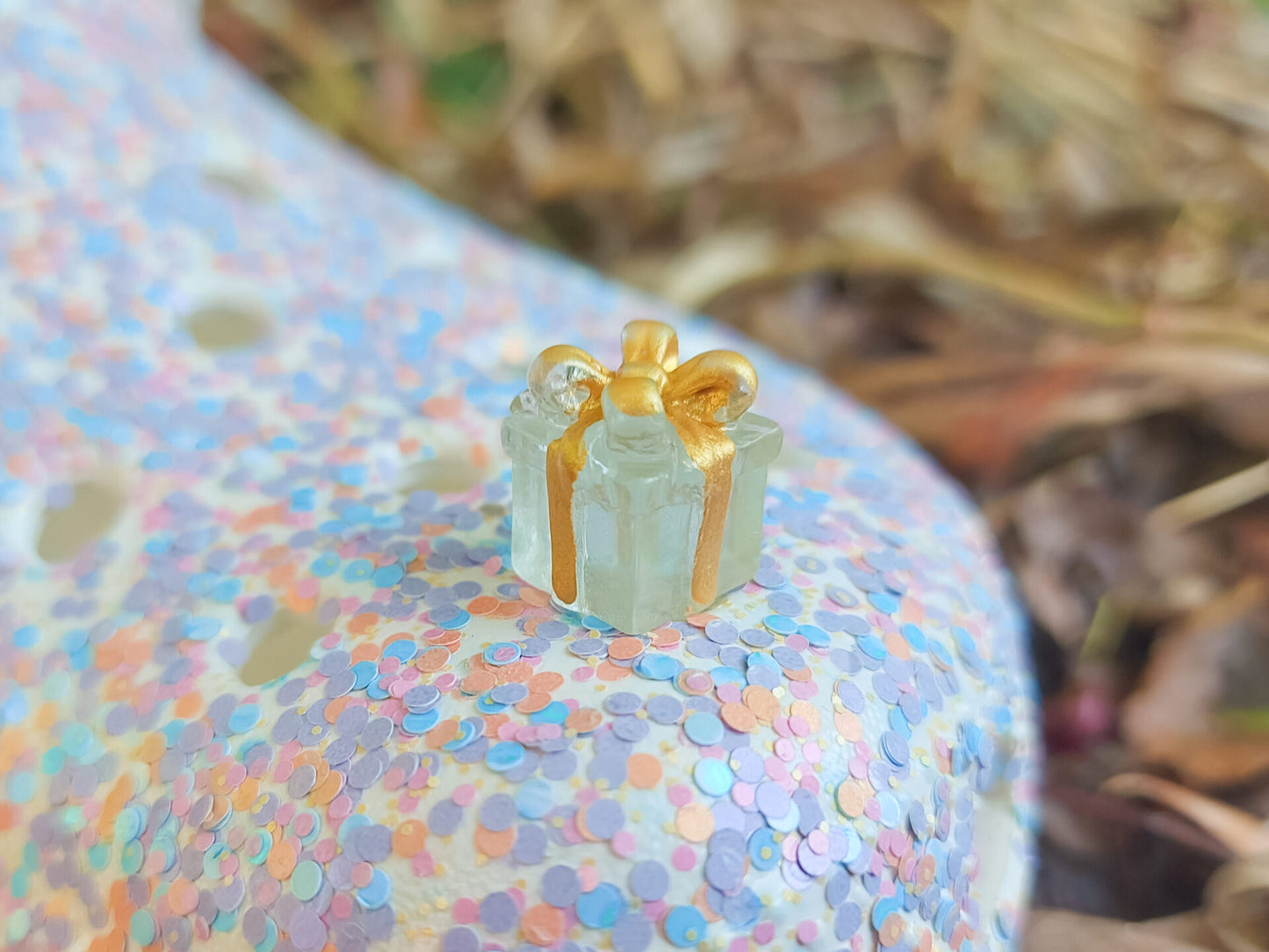 Glow in the dark christmas present charms on a colorful shoes shoe. It is a gift box with a big ribbon on top available in blue, pink, green, orange and peach. Xmas-themed perfect for the holidays.