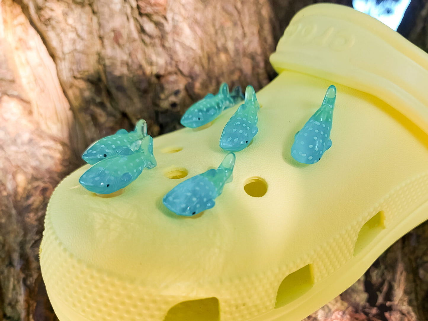 Whale shark shoe charms in turquoise blue with white spots, clipped onto a bright yellow pair of shoes shoes, adding a playful oceanic touch to the footwear.