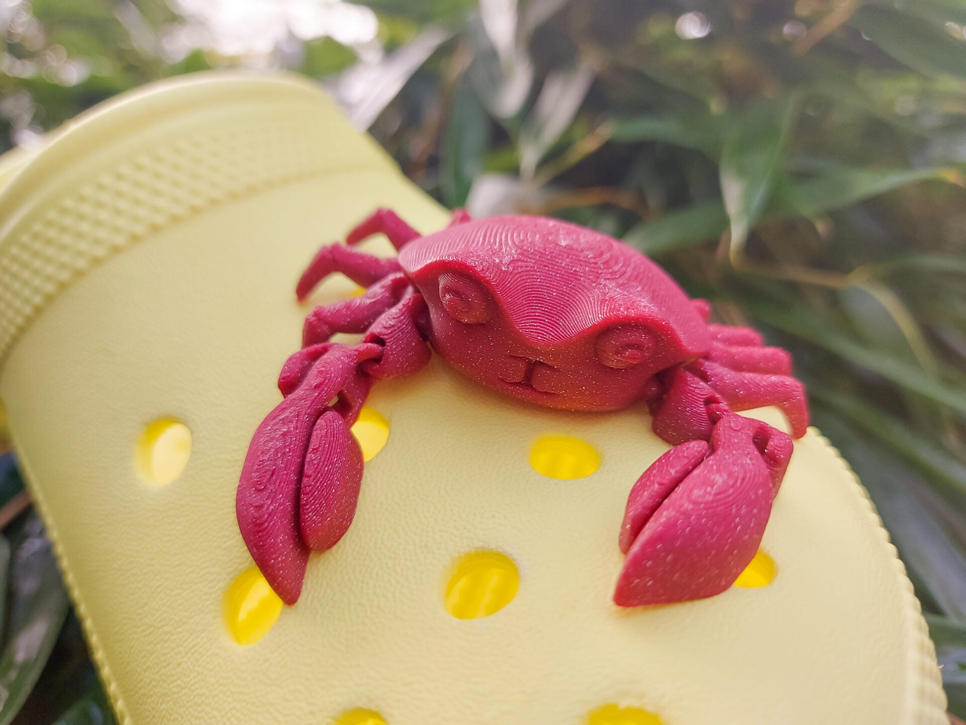 A 3D-printed, flexible red crab charm attached to a yellow shoe shoe. The crab charm features articulated claws and realistic texture, adding a fun and beach-inspired touch to the footwear. Perfect for ocean lovers and those seeking unique shoe accessories.