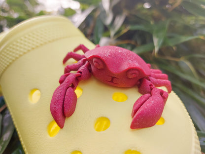 A 3D-printed, flexible red crab charm attached to a yellow shoe shoe. The crab charm features articulated claws and realistic texture, adding a fun and beach-inspired touch to the footwear. Perfect for ocean lovers and those seeking unique shoe accessories.
