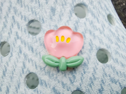 Close-up of a shoe decorated with a 5-piece jelly charm set, including two flowers, a yellow duck, a bunny with a pink bow, and a red mushroom. Each charm has a cute, soft, jelly-like appearance, adding a fun and playful vibe to the footwear.