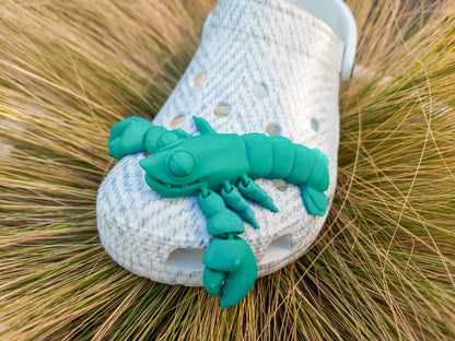 Colorful 3D printed flexi lobster charms in green, orange, yellow, and red, attached to shoes shoes. Each lobster has a segmented, flexible body and realistic details, adding a playful marine-inspired style to the shoes.