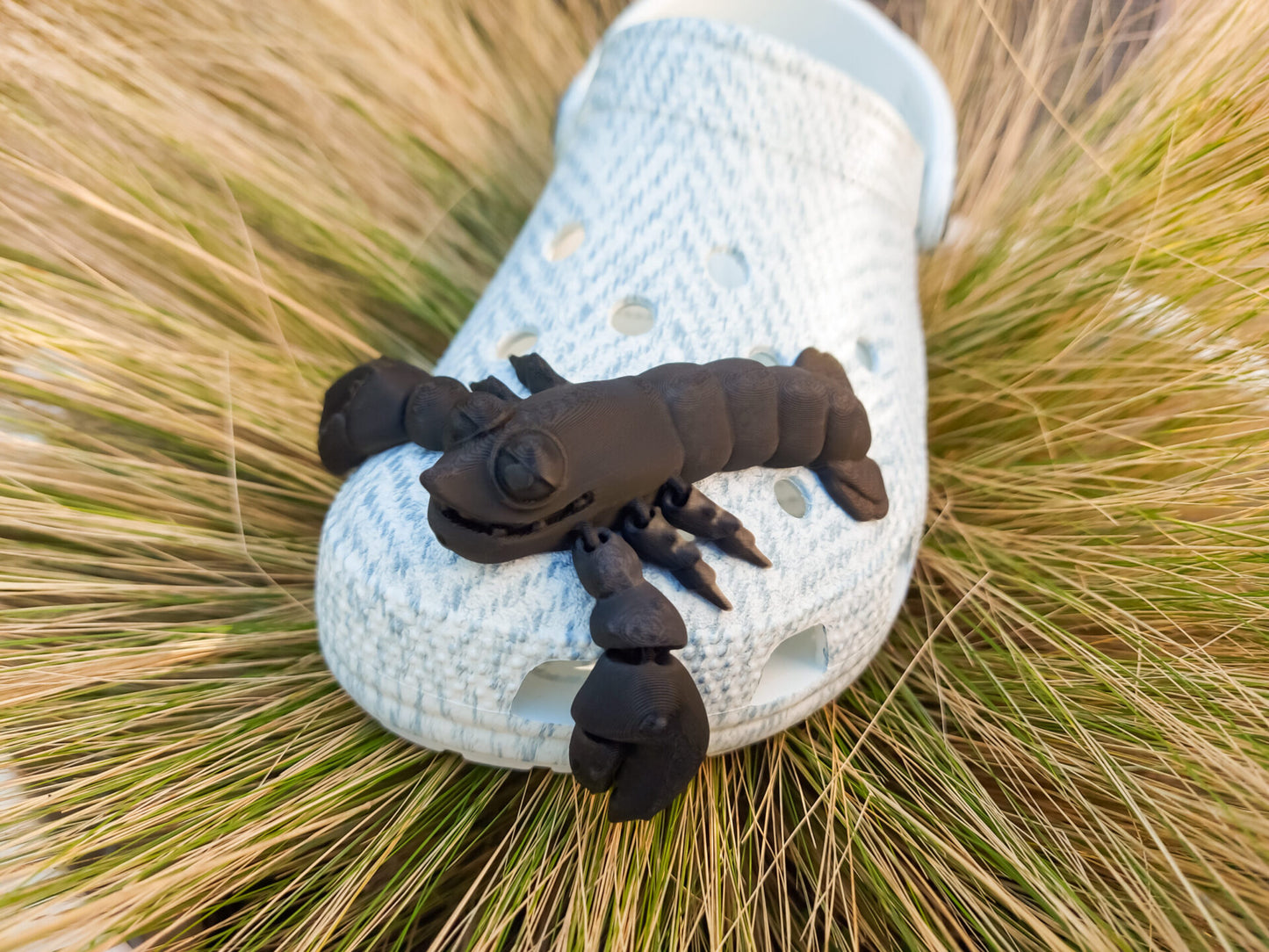 Colorful 3D printed flexi lobster charms in green, orange, yellow, and red, attached to shoes shoes. Each lobster has a segmented, flexible body and realistic details, adding a playful marine-inspired style to the shoes.