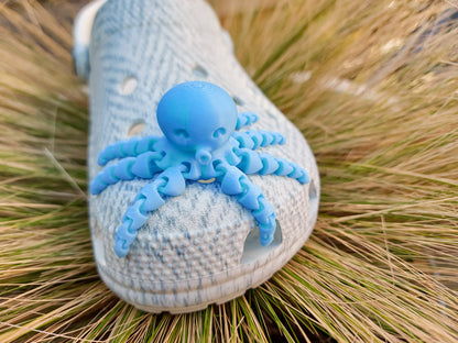 A set of colorful 3D printed flexi octopus charms in red, blue, green, and black, displayed on shoes shoes. Each charm features flexible, articulated tentacles, adding a fun ocean-themed touch and unique texture to the shoes.