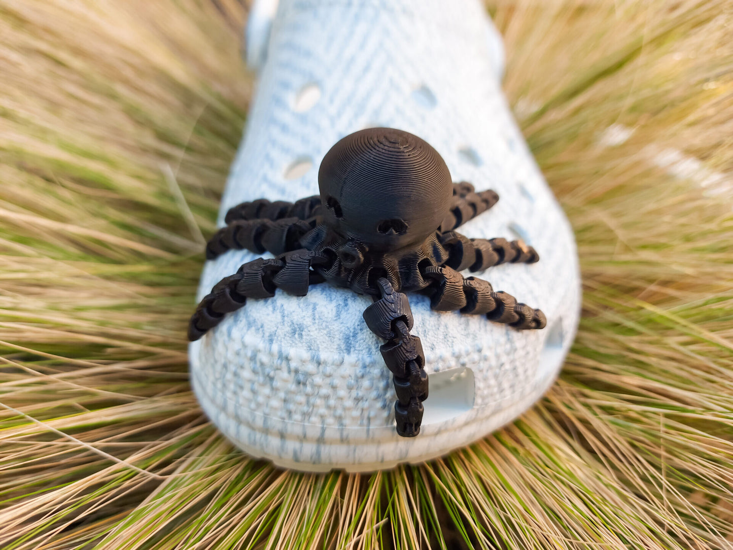 A set of colorful 3D printed flexi octopus charms in red, blue, green, and black, displayed on shoes shoes. Each charm features flexible, articulated tentacles, adding a fun ocean-themed touch and unique texture to the shoes.