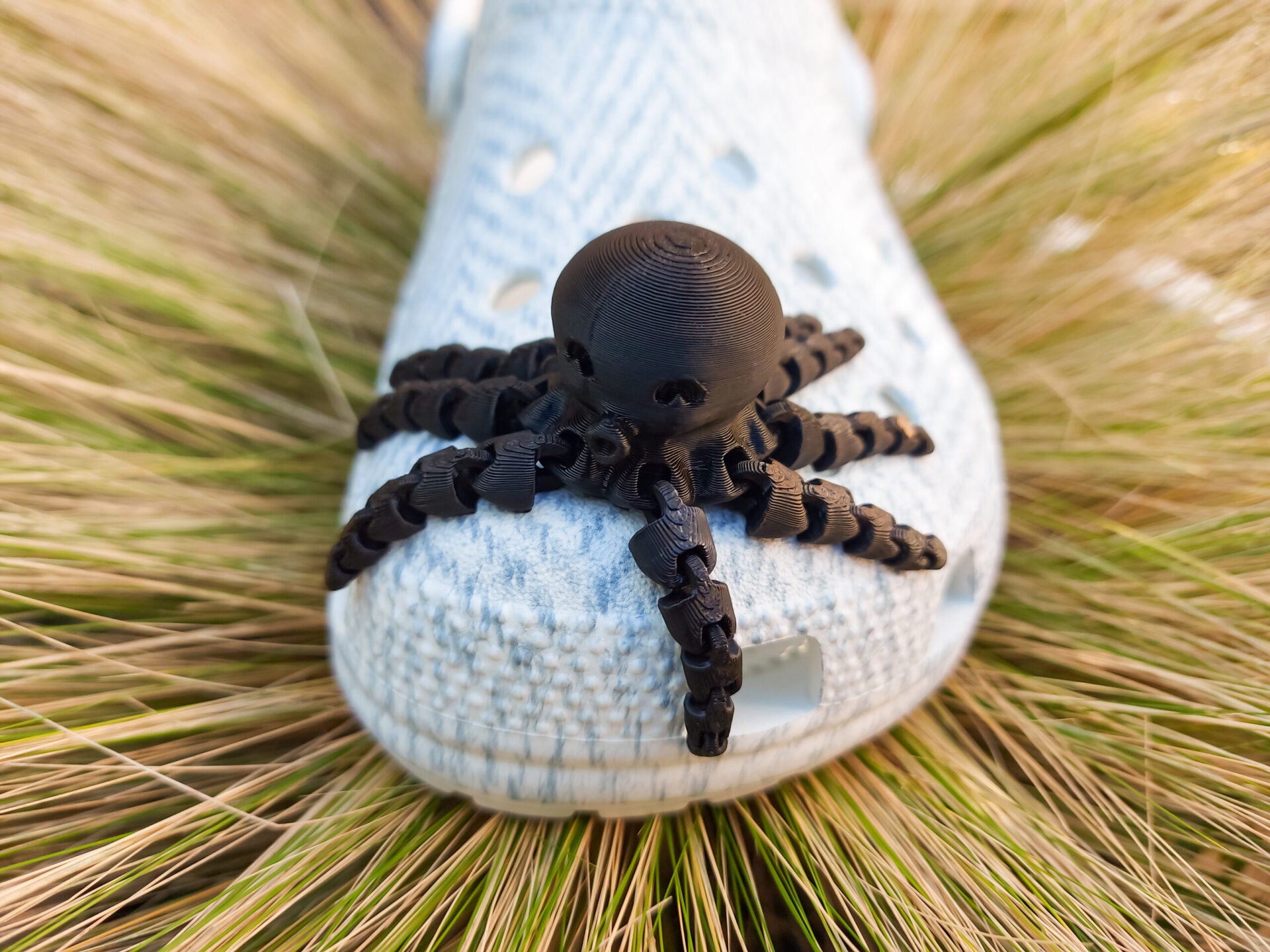 A set of colorful 3D printed flexi octopus charms in red, blue, green, and black, displayed on shoes shoes. Each charm features flexible, articulated tentacles, adding a fun ocean-themed touch and unique texture to the shoes.