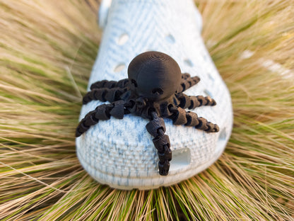 A set of colorful 3D printed flexi octopus charms in red, blue, green, and black, displayed on shoes shoes. Each charm features flexible, articulated tentacles, adding a fun ocean-themed touch and unique texture to the shoes.