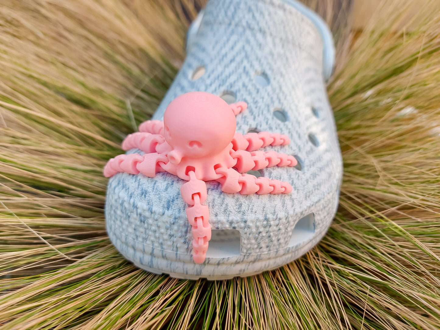 A set of colorful 3D printed flexi octopus charms in red, blue, green, and black, displayed on shoes shoes. Each charm features flexible, articulated tentacles, adding a fun ocean-themed touch and unique texture to the shoes.