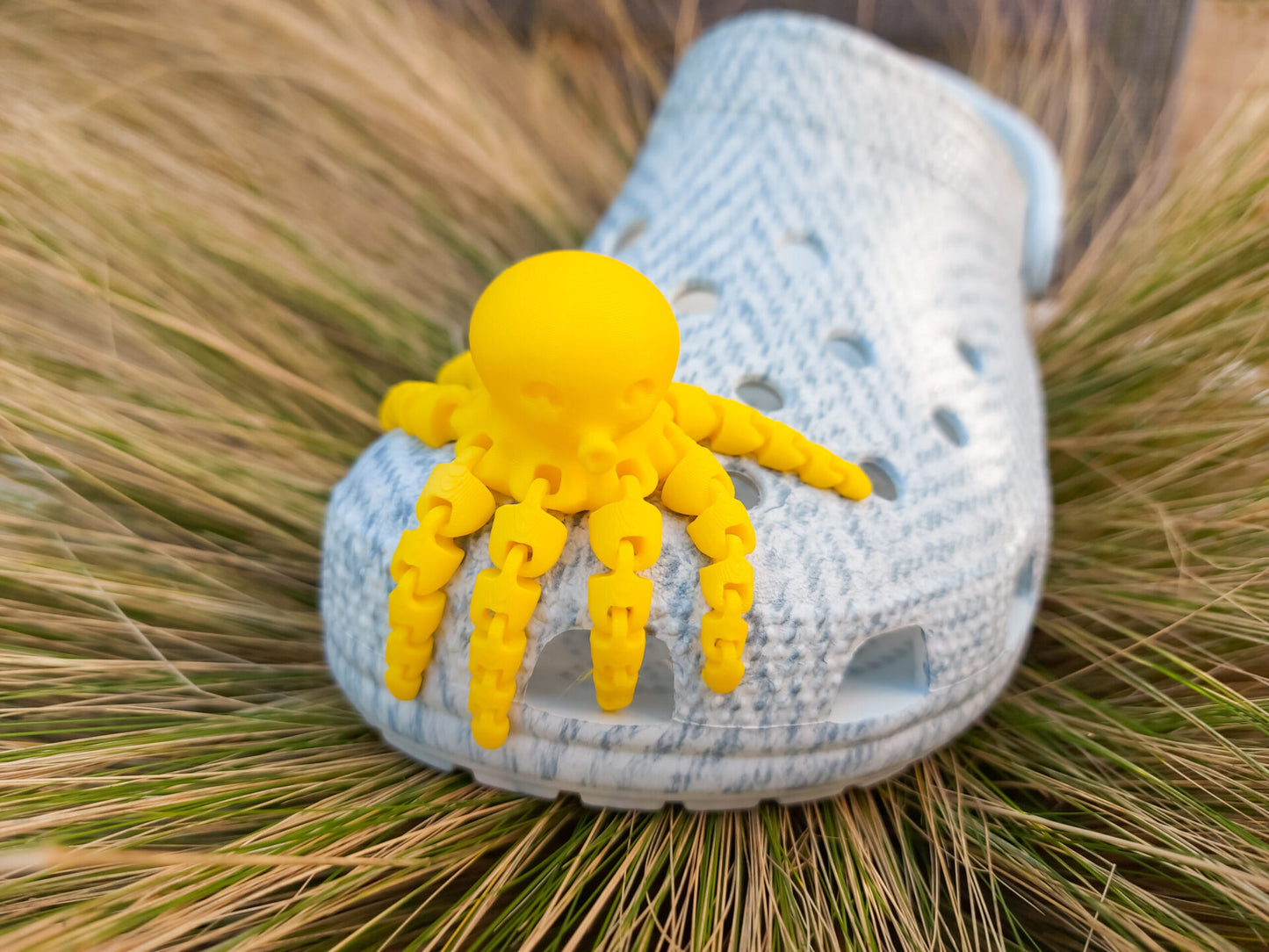 A set of colorful 3D printed flexi octopus charms in red, blue, green, and black, displayed on shoes shoes. Each charm features flexible, articulated tentacles, adding a fun ocean-themed touch and unique texture to the shoes.