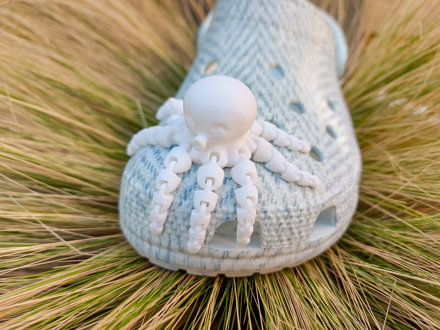 A set of colorful 3D printed flexi octopus charms in red, blue, green, and black, displayed on shoes shoes. Each charm features flexible, articulated tentacles, adding a fun ocean-themed touch and unique texture to the shoes.