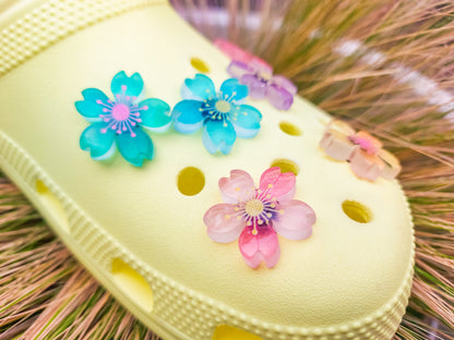 Glow-in-the-dark cherry blossom shoe charms in six colors—pink, dark pink, purple, blue, green, and orange—adding a soft, luminous effect to shoes with flower-themed elegance.
