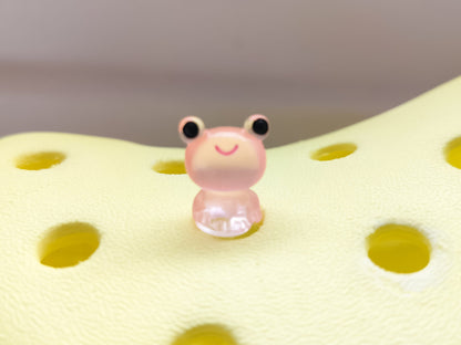 Glow-in-the-dark frog charms on a yellow shoes shoe. These playful and luminous accessories add a fun, froggy touch to your footwear, making them perfect for customizing your shoes with a whimsical and adventurous vibe.