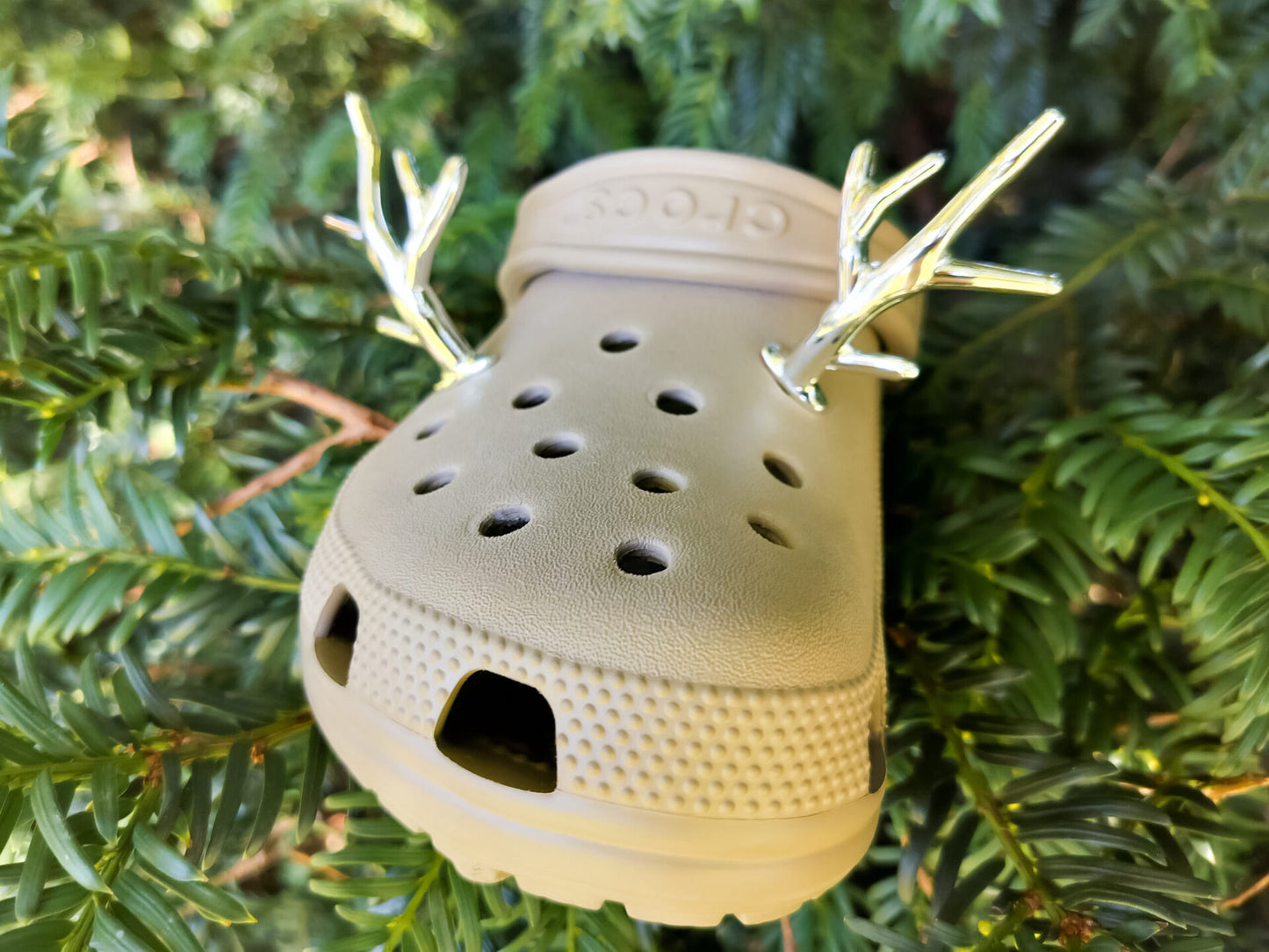 A pair of tan shoes decorated with red and gold reindeer antler charms, perched on a tree branch, perfect for holiday-themed footwear decorations. Available in multiple festive colors.