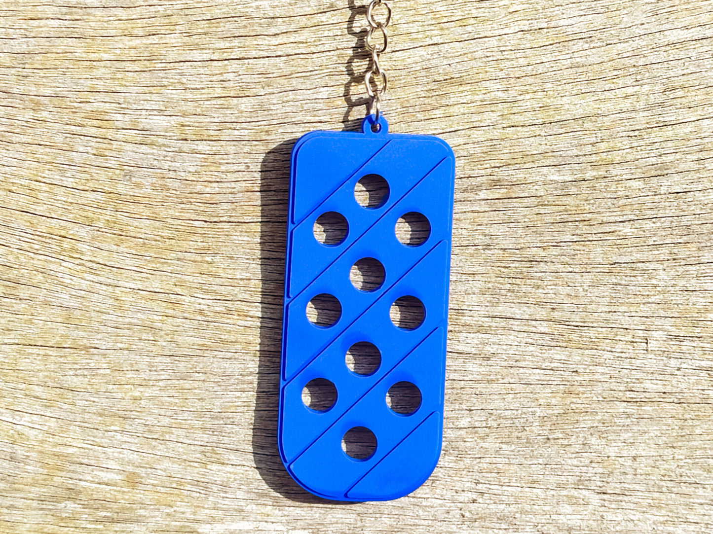 Three PVC keychains in pink, white, and blue with holes designed to hold shoe charms. Each keychain displays a unique set of charms, including candy-themed and colorful glitter charms, showcasing a playful and customizable accessory for charm lovers.