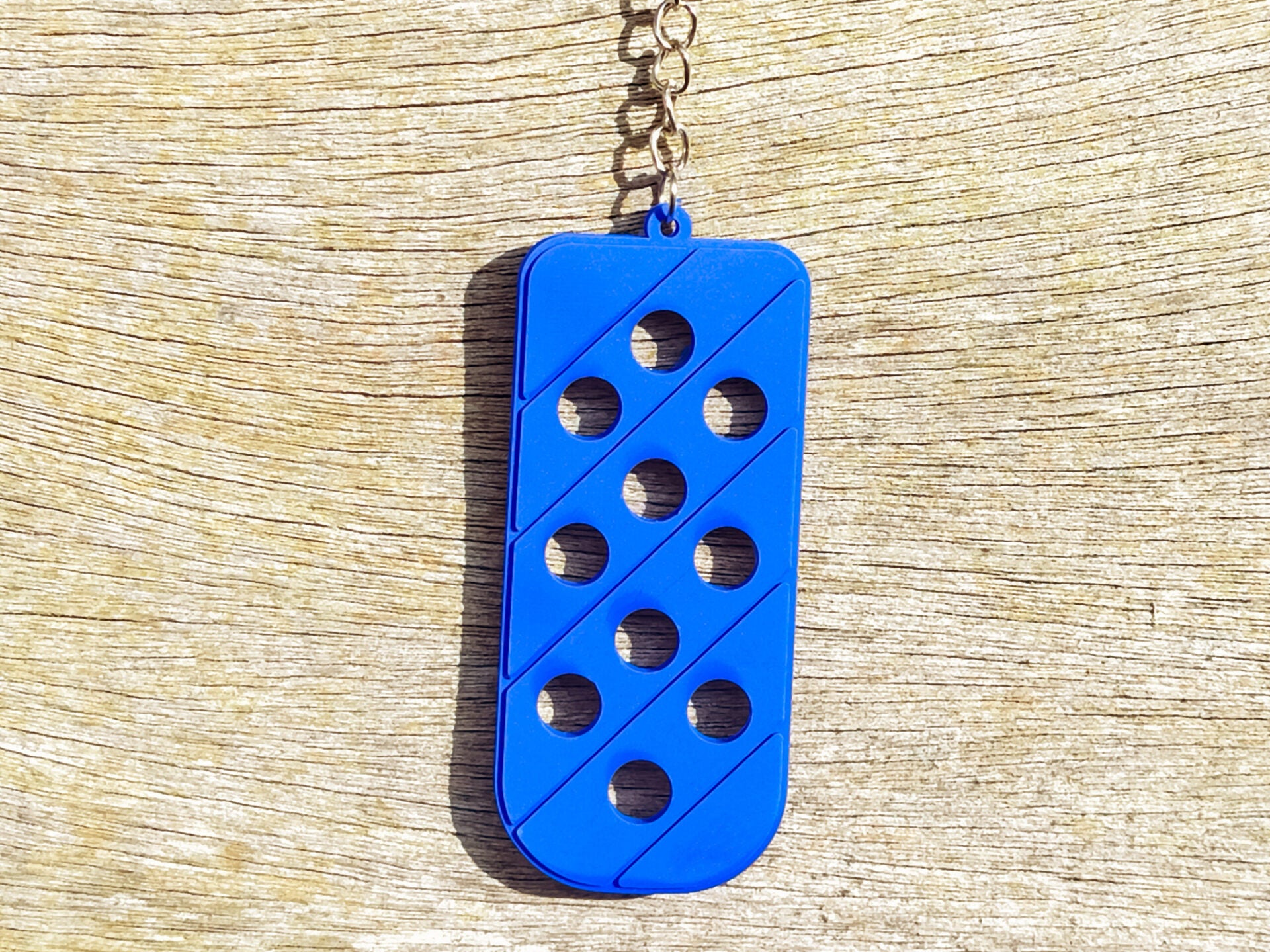 Three PVC keychains in pink, white, and blue with holes designed to hold shoe charms. Each keychain displays a unique set of charms, including candy-themed and colorful glitter charms, showcasing a playful and customizable accessory for charm lovers.