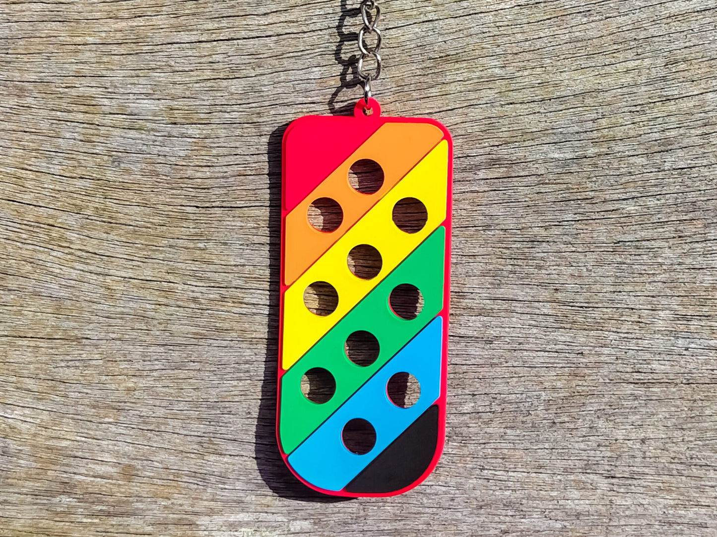 Three PVC keychains in pink, white, and blue with holes designed to hold shoe charms. Each keychain displays a unique set of charms, including candy-themed and colorful glitter charms, showcasing a playful and customizable accessory for charm lovers.