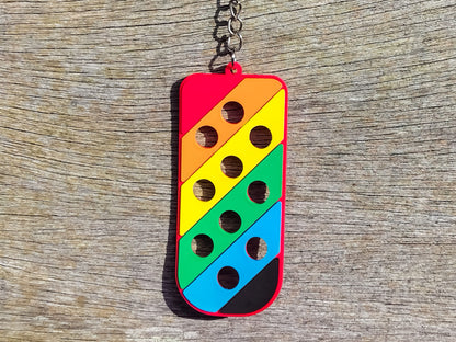 Three PVC keychains in pink, white, and blue with holes designed to hold shoe charms. Each keychain displays a unique set of charms, including candy-themed and colorful glitter charms, showcasing a playful and customizable accessory for charm lovers.