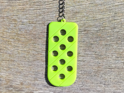 Three PVC keychains in pink, white, and blue with holes designed to hold shoe charms. Each keychain displays a unique set of charms, including candy-themed and colorful glitter charms, showcasing a playful and customizable accessory for charm lovers.