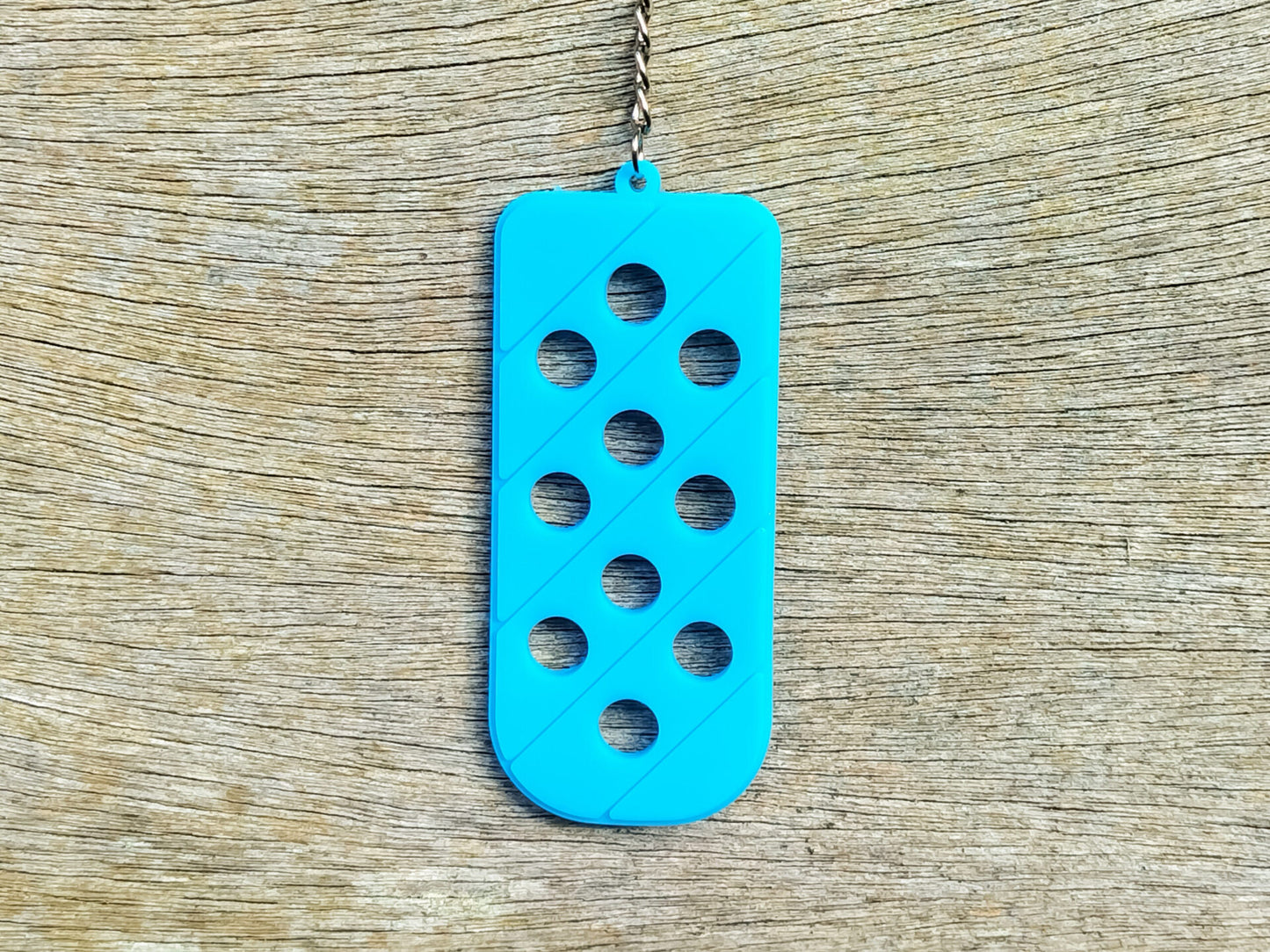 Three PVC keychains in pink, white, and blue with holes designed to hold shoe charms. Each keychain displays a unique set of charms, including candy-themed and colorful glitter charms, showcasing a playful and customizable accessory for charm lovers.