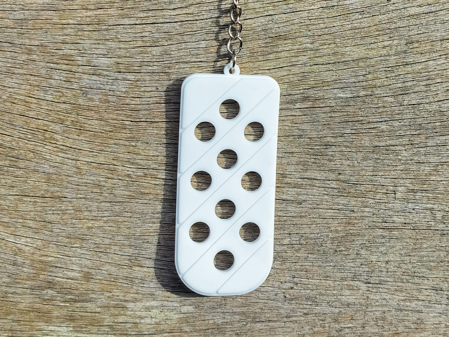 Three PVC keychains in pink, white, and blue with holes designed to hold shoe charms. Each keychain displays a unique set of charms, including candy-themed and colorful glitter charms, showcasing a playful and customizable accessory for charm lovers.